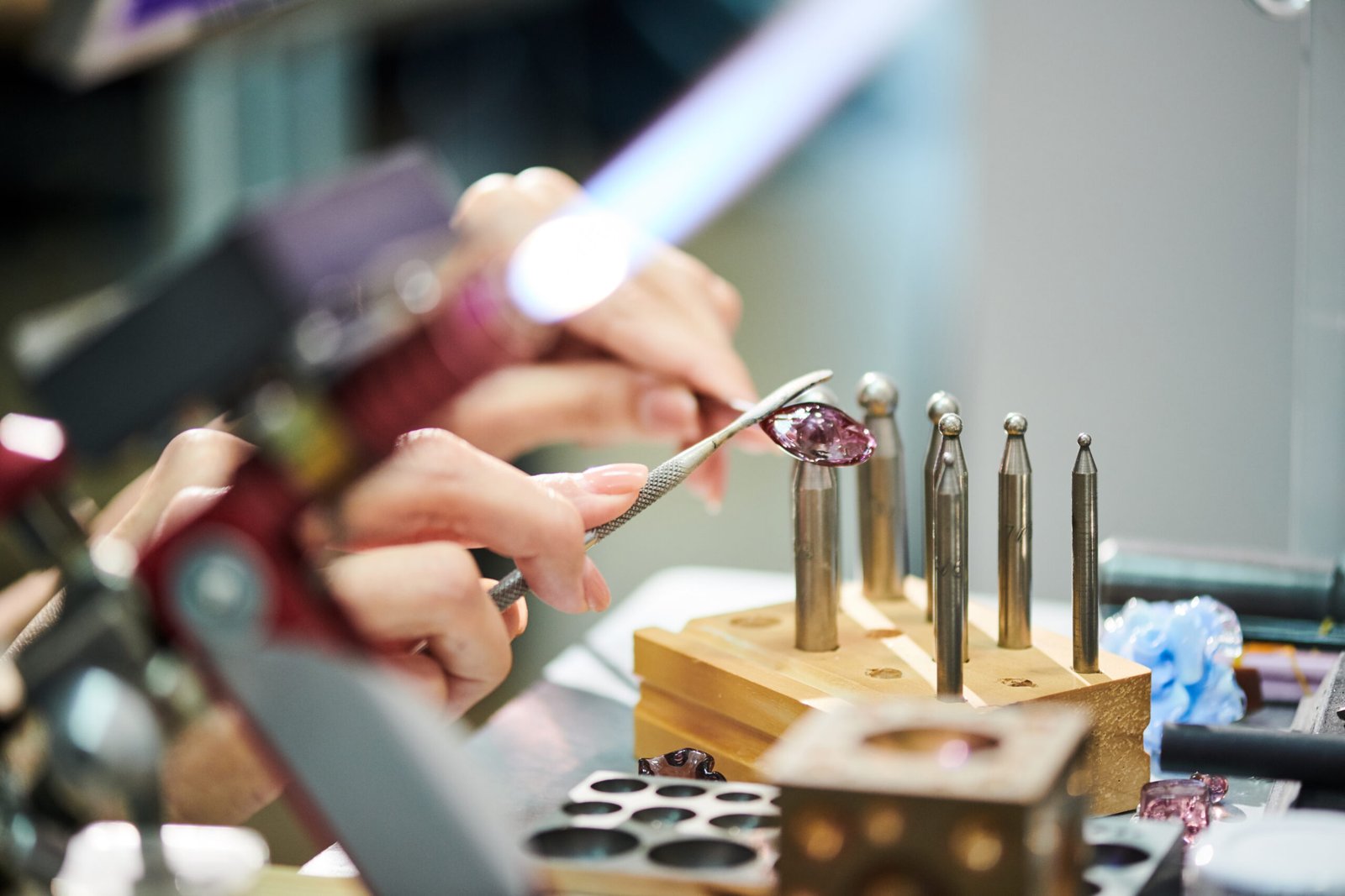 Closeup of unrecognizable woman shaping glass while making beautiful handmade jewelry in glassworking studio, copy space